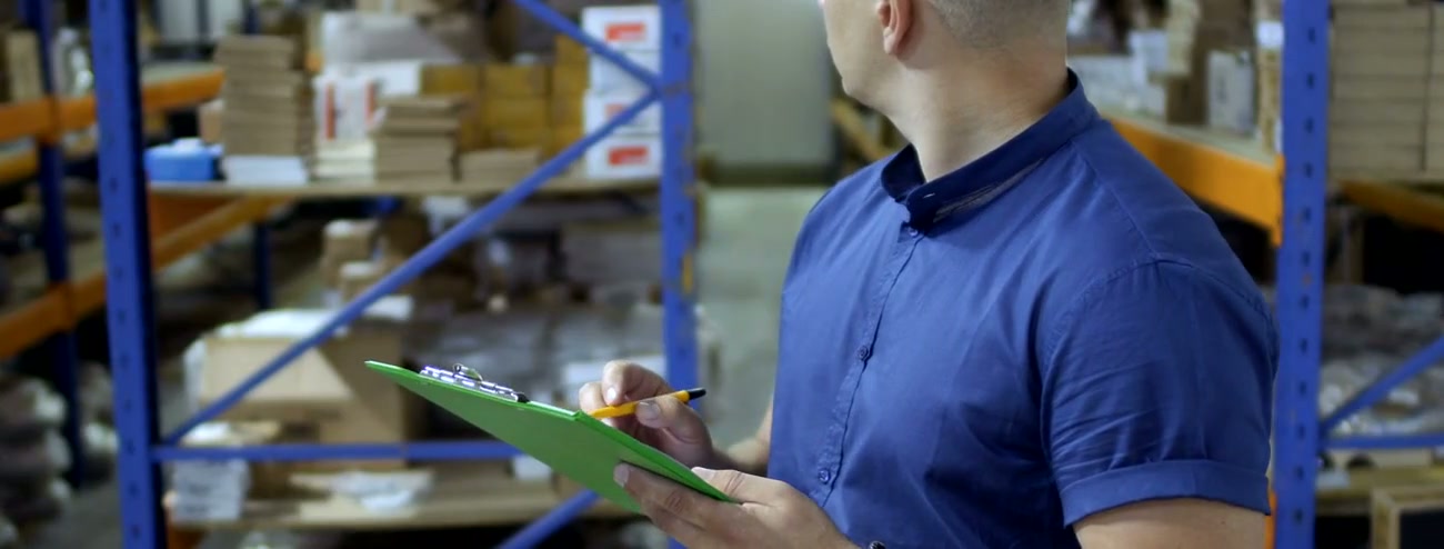 Factory worker checking packed goods inventory before dispatch